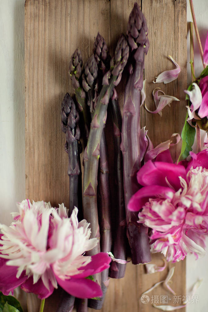 木质厨房餐盘上装饰有美丽牡丹的鲜绿紫芦笋可作为背景