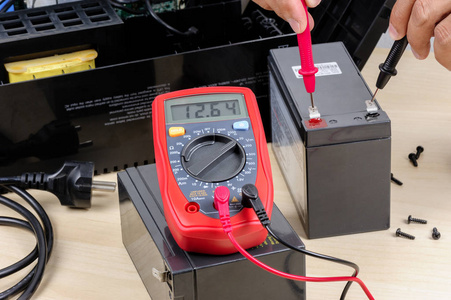 技术人员用万用表测量ups(不间断电源)电池的电压.照片