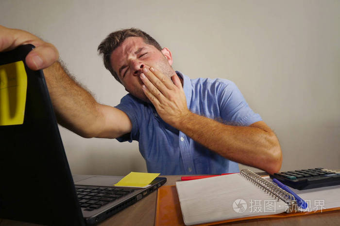 困乏疲惫的人在笔记本电脑上工作,打哈欠,在办公室里