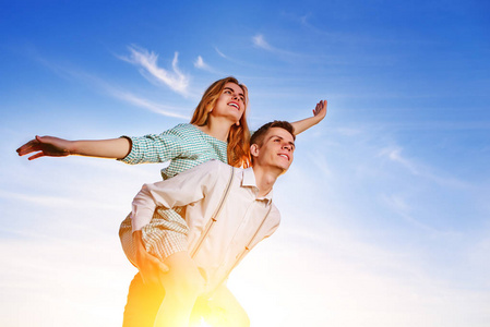 跟恋人像朋友年轻人背着欢快的女朋友,就像天空背景下的飞机.照片