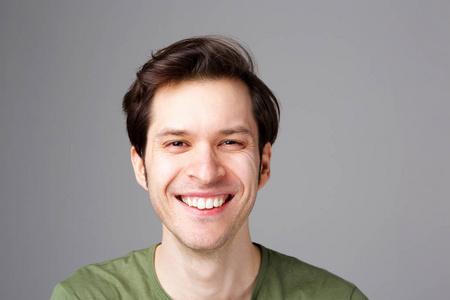 站在灰色墙边的快乐年轻人的肖像照片