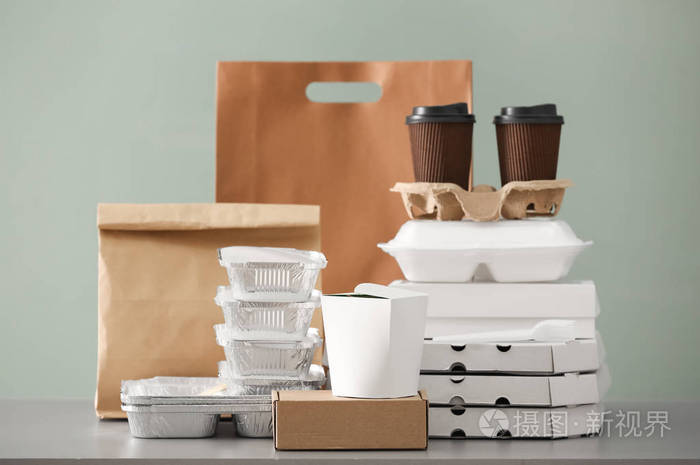 不同的包装和纸箱杯在桌子上的颜色背景。 食物供应服务
