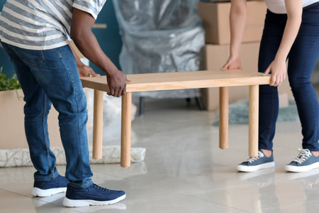 种族房子一对不同种族的夫妇在新房子里搬桌子照片