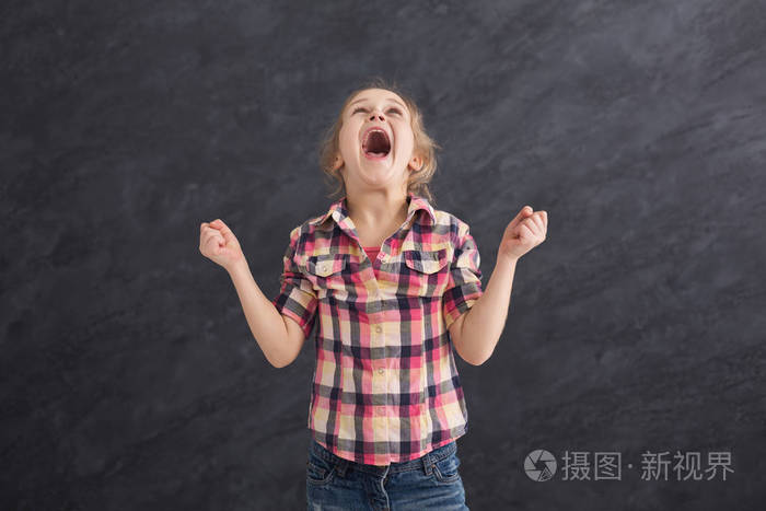愤怒的小女孩在灰色背景下哭泣