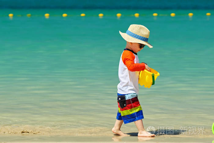 戴帽子的小孩在沙滩上玩沙滩玩具