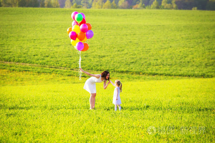 外面有孩子的女人. 女孩在绿色的草地上给母亲野花.