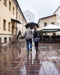 雨天街道在雨天, 幸福的情侣在城市街道的伞下照片