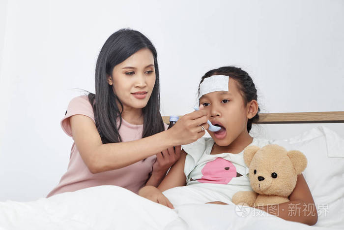 亚洲母亲在床上给女儿喂止咳药