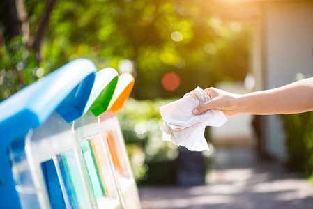 女人手拿着,把废纸扔进垃圾桶.照片