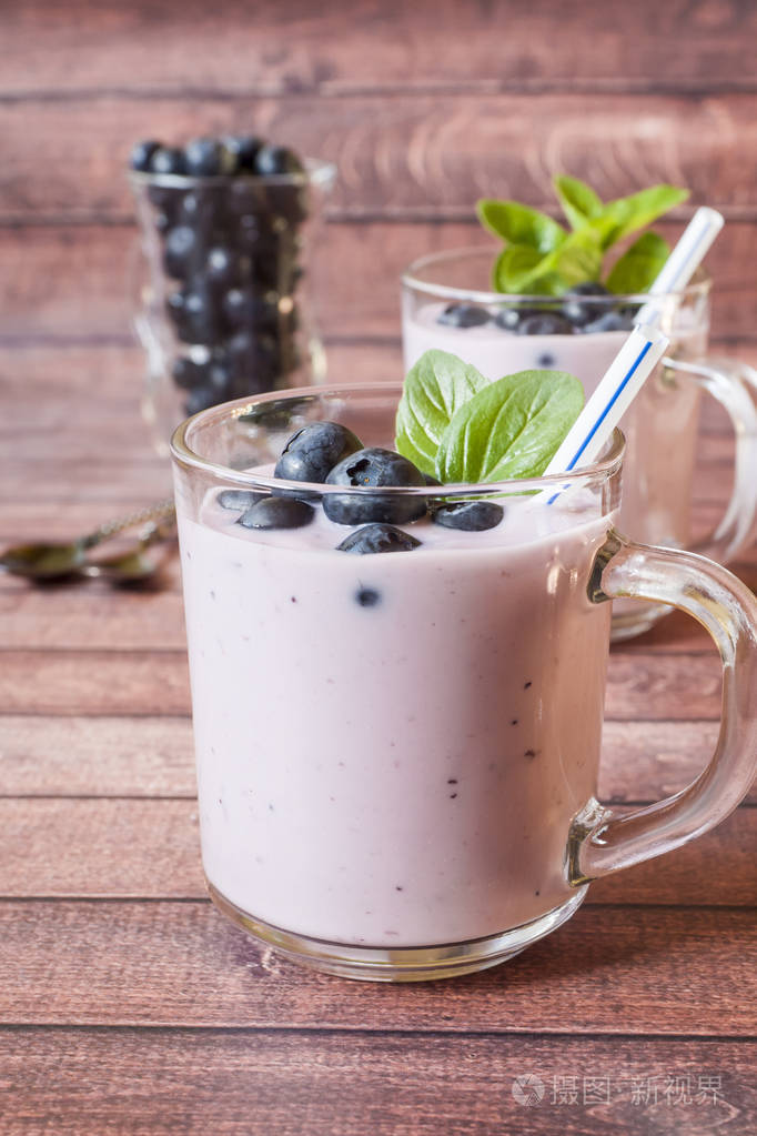 蓝莓酸奶在玻璃杯中新鲜蓝莓和薄荷在木制的乡村桌子上