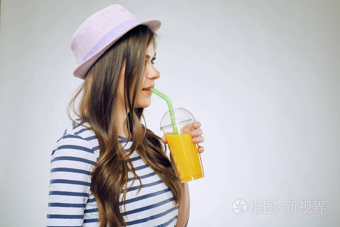 戴帽子的女人从塑料杯里喝橙汁