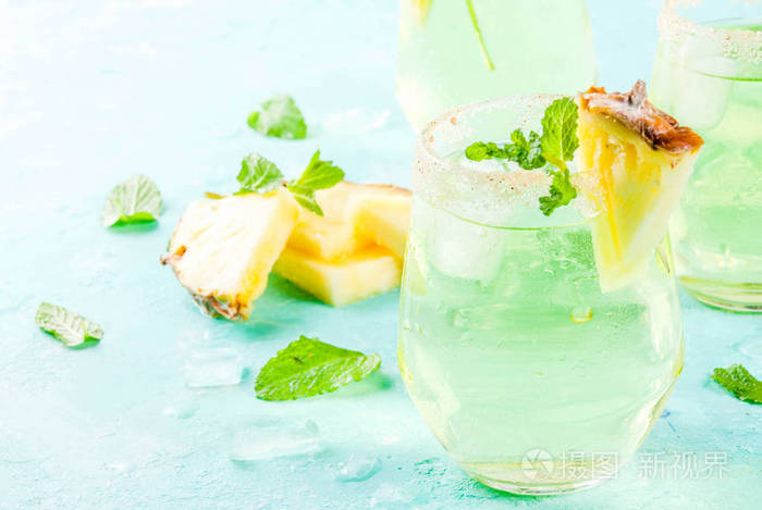 热带饮料菠萝汁玛格丽塔鸡尾酒与新鲜薄荷浅蓝色背景复制空间