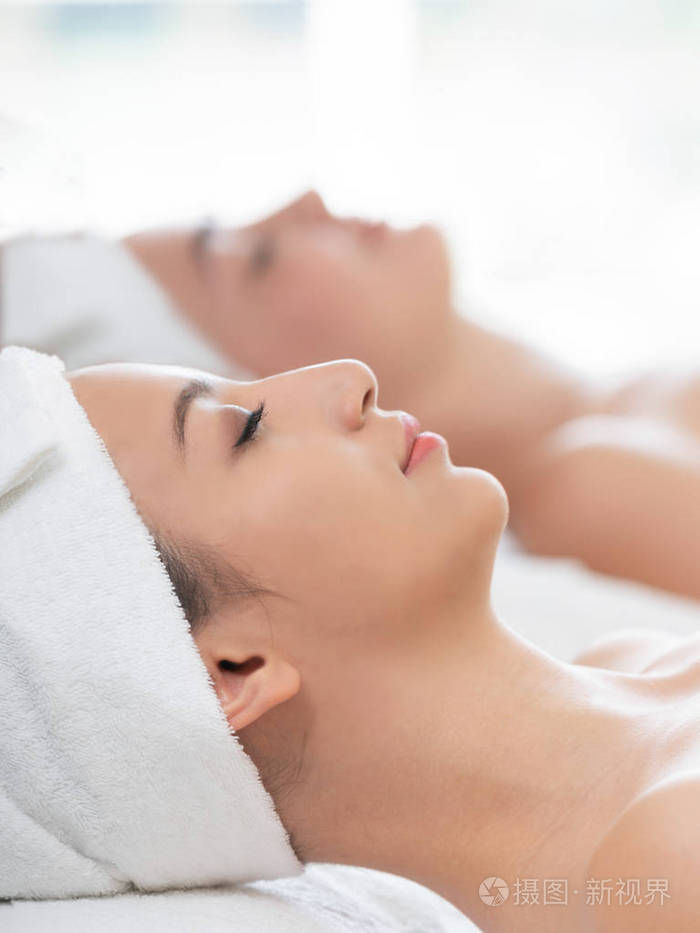 放松的年轻女子躺在水疗床上,准备在豪华水疗中心进行面部治疗和按摩.