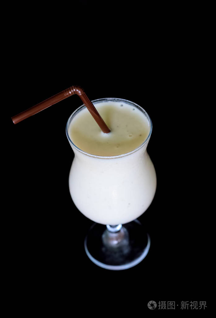 黑色背景下的白色鸡尾酒. 牛奶冰沙在玻璃和稻草. 奶昔俯视孤立.