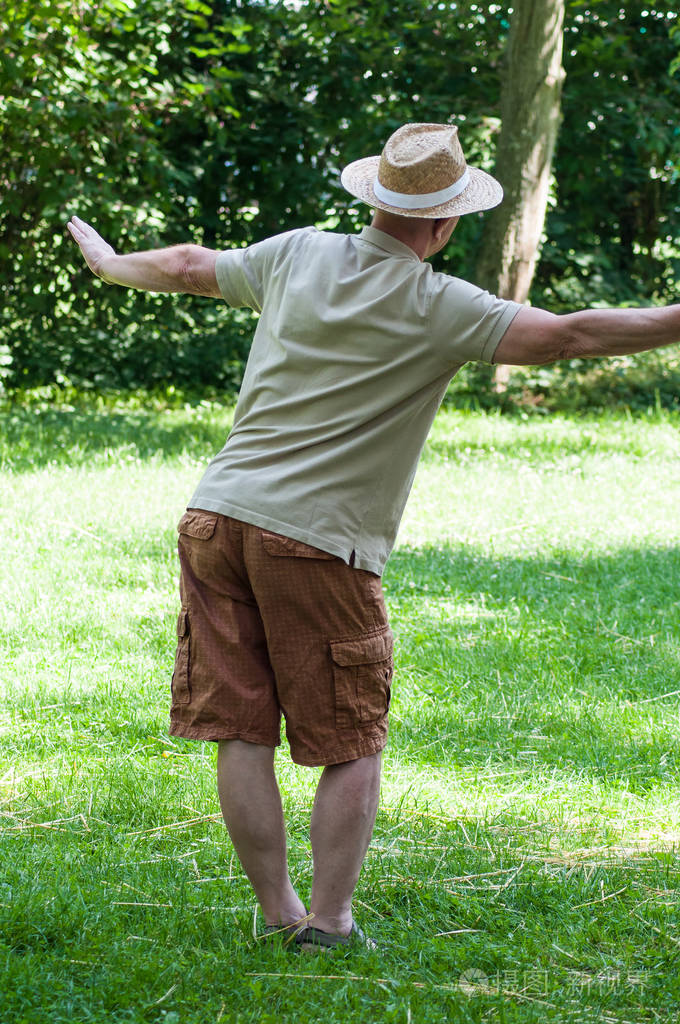 戴帽子的老人肖像在城市公园背面拍摄太极拳
