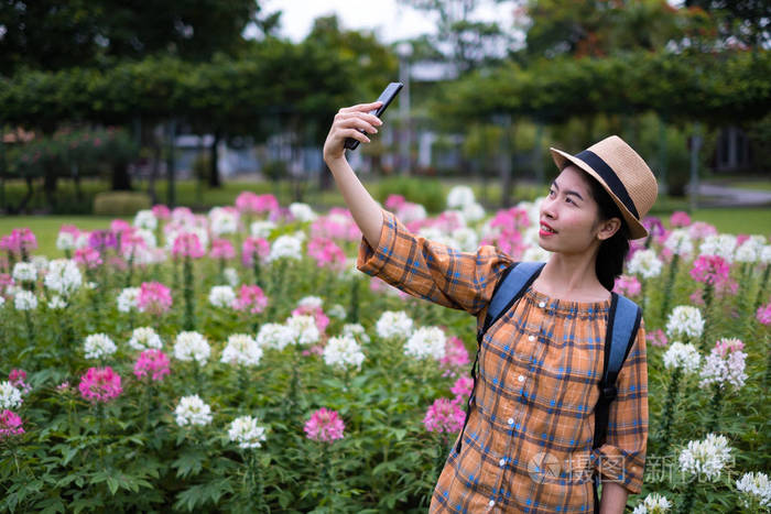 亚洲女游客正在蜘蛛花园用智能手机拍照和自拍. 在假期里旅行.