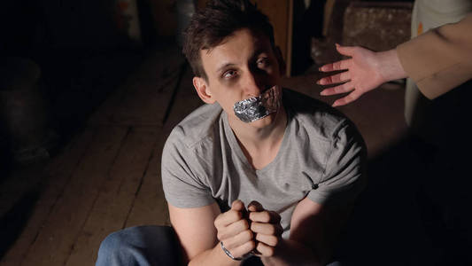 英俊的男人,有一只黑眼睛,双手被绑在一个黑暗的房间里.照片