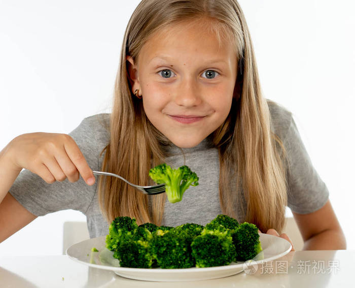 快乐的金发女孩吃她的西兰花蔬菜健康儿童饮食观念