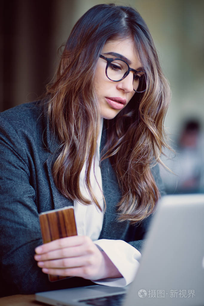 年轻的现代女人坐在咖啡馆里用笔记本电脑