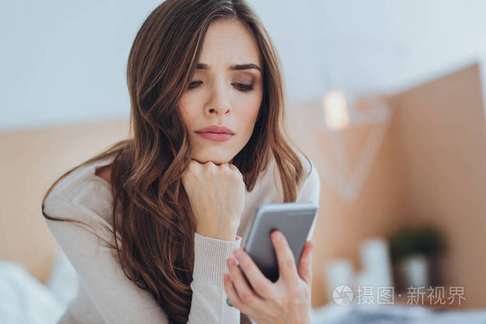 可怜的年轻女人看着她的智能手机