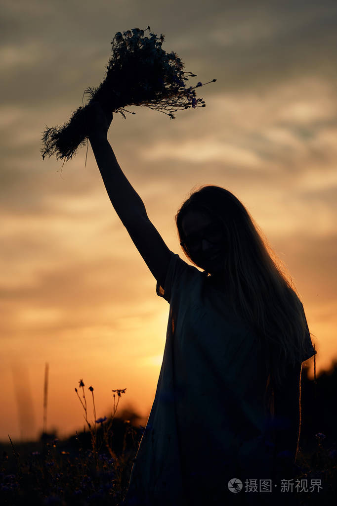在田野里拿着一束雏菊和向日葵的女孩