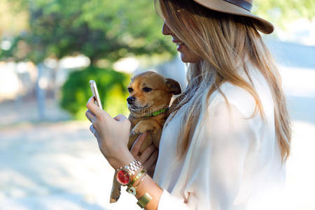 漂亮的年轻女人带着她的狗用手机。