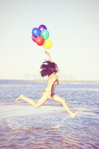 美丽和运动的黑发女孩，五颜六色的气球跳跃