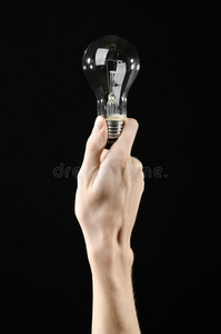 能源消耗和节能主题人手拿灯泡在黑色背景在工作室