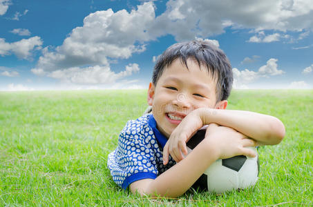 男孩在球场上对他的足球微笑