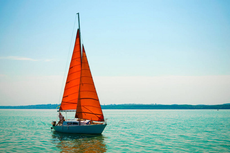 湖面上有朱红色帆的帆船照片