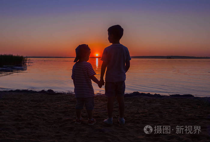两个男孩兄弟看美丽的日落
