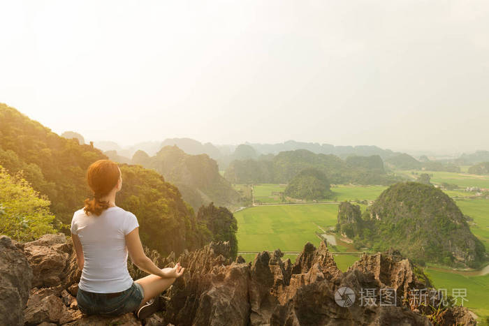 年轻女子在山顶练习瑜伽时保持冷静和冥想,风景优美