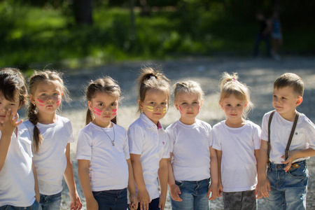 一群穿着白 t恤衫的小孩子们在夏天排队排成一行.照片