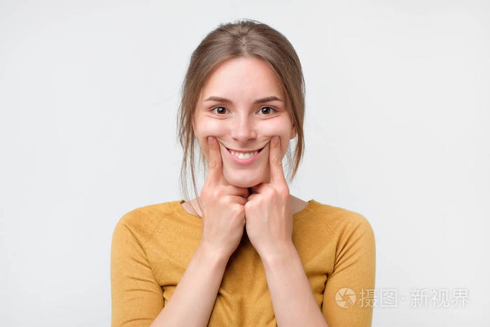 拍摄的美丽的白种少女女孩强迫微笑, 握住她的手指在她的嘴唇边缘