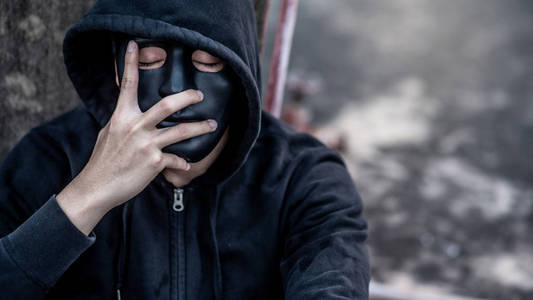 神秘人戴着黑色面具,穿着帽衫,闭上眼睛想着什么.