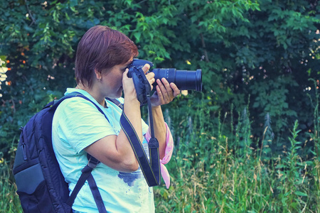 takepictures一个穿着白色t恤背包的女孩坐在草地上拍摄镜头照片