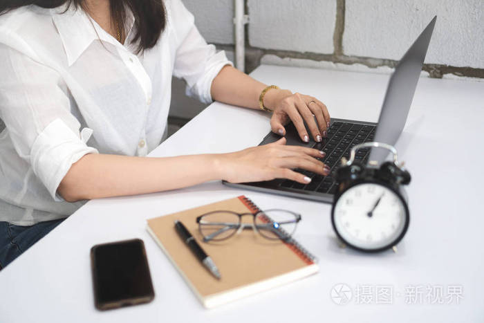 照片 年轻女子使用笔记本电脑在家庭办公室的白色桌子上工作,带智能