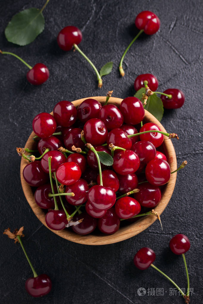 黑色背景的木碗里的新鲜樱桃新鲜成熟的红色甜樱桃垂直