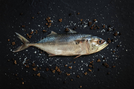 海盐和鱼新鲜生鲭鱼的顶部视图与海盐和胡椒在黑色背景.照片
