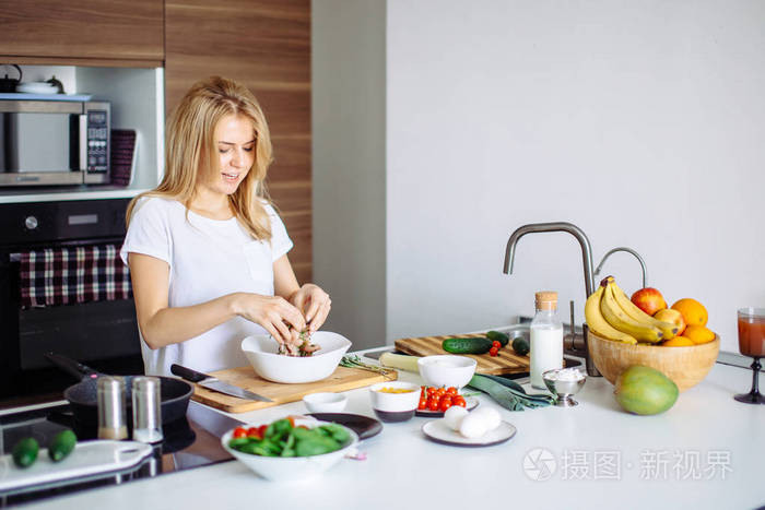 在厨房做晚餐的白色t恤的幸福女性妻子肖像