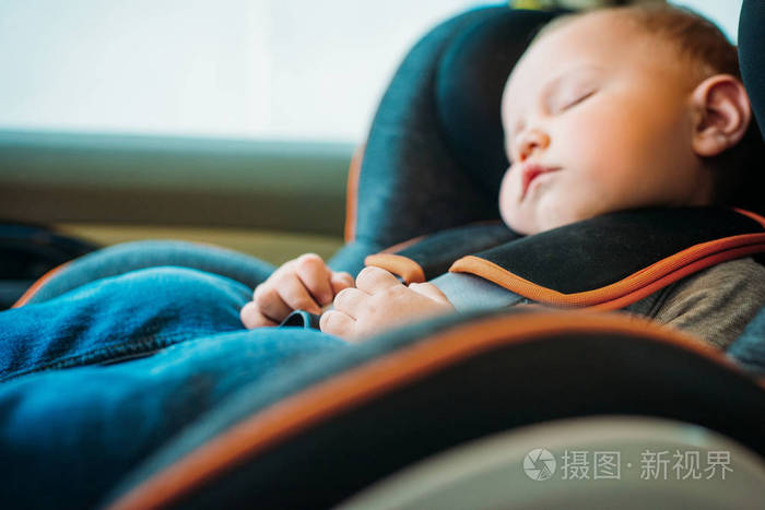 在汽车上睡在儿童安全座椅上的可爱的小婴儿的肖像。