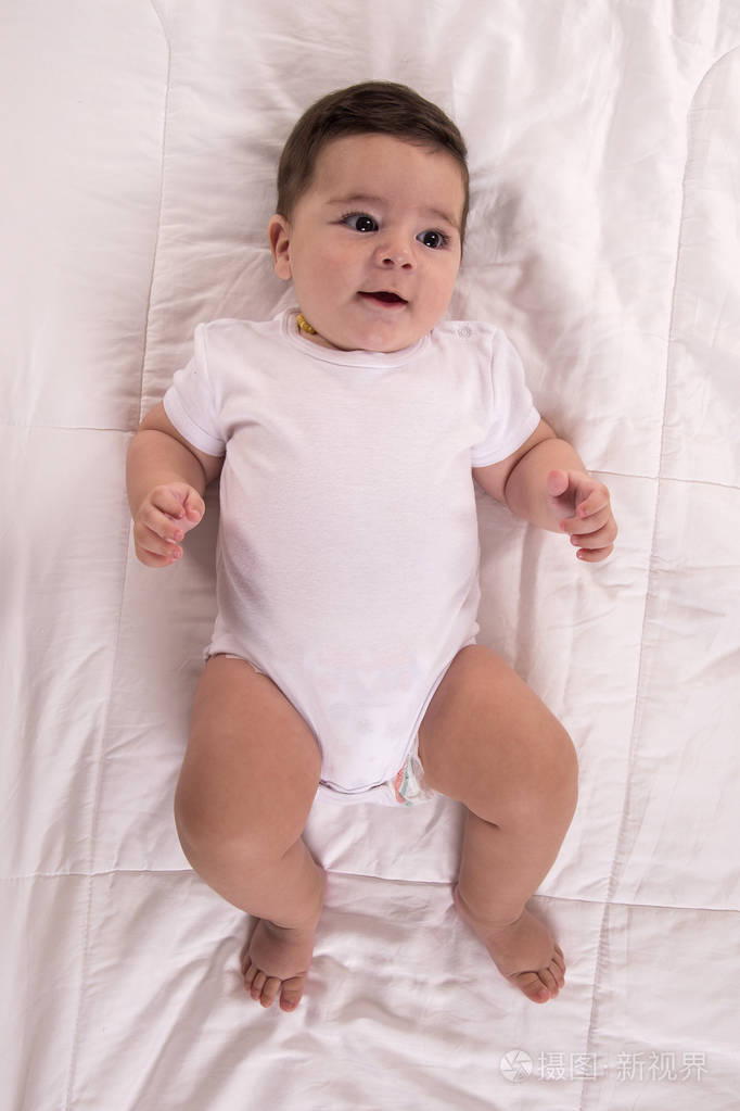 顶部视图和特写肖像可爱可爱的可爱小男孩穿白色的身体在卧室看相机