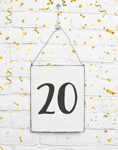 20岁生日派对卡片文字用金色纸屑数字20金属板白砖背景照片