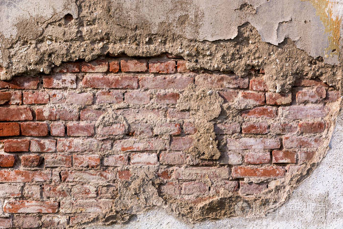 油漆痛苦的墙面. 红色石墙背景. 破旧的建筑立面,有损坏的石膏.