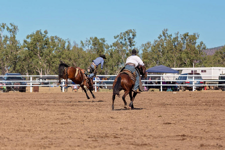 牛仔在乡村牛仔竞技比赛中骑着一匹驯马照片