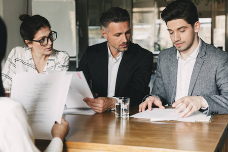 人坐在办公室的桌子上,在面试,商业生涯和招聘概念期间与年轻女性交谈