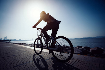 骑自行车的人在日出海岸公路上的剪影照片