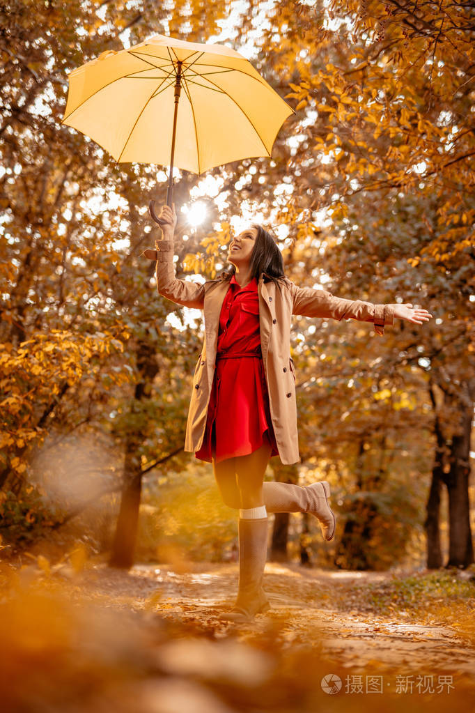 年轻女子在阳光明媚的秋天公园散步