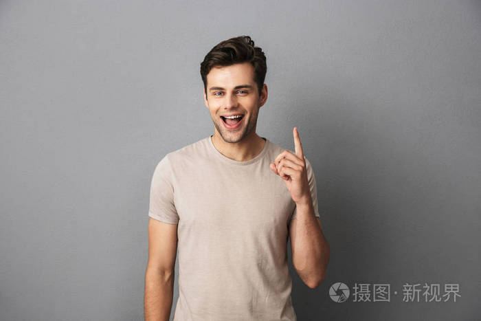 一个30多岁的快乐男人穿着t恤露出手指露出快乐的微笑孤立在灰色背景
