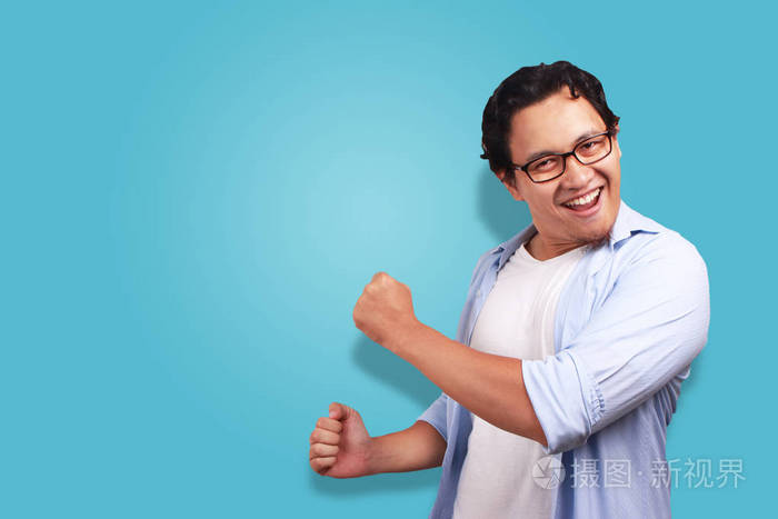 年轻的亚洲男人穿着白色和蓝色的衬衫,高兴地表达着庆祝胜利的表情.